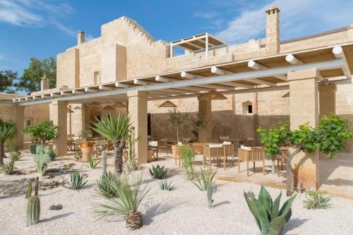 an outdoor patio with tables and chairs and plants at Masseria Donna Menga - The Leading Hotels of the World in Torre Lapillo