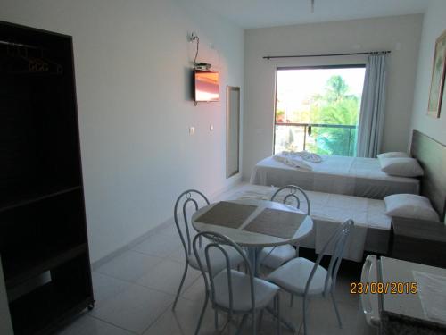 a room with two beds and a table and chairs at Pousada Sky Beach Flat in Porto De Galinhas