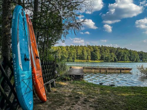 two surfboards are leaning against a fence next to a lake at CzillasOrle luksusowy dom nad samym brzegiem jeziora Orle koło Augustowa in Płaska