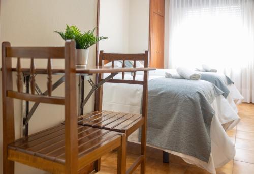 a bedroom with a bed and two wooden chairs at Pensión A Codeseira Melide in Melide
