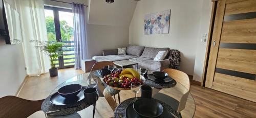 a living room with a table with a bowl of fruit at Arkady House in Olsztynek