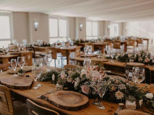 a room with wooden tables with flowers and wine glasses at Savannah Game Lodge, Wedding Venue and River Retreat in Parys