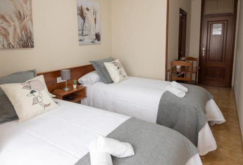 a bedroom with two beds with towels on them at Pensión A Codeseira Melide in Melide