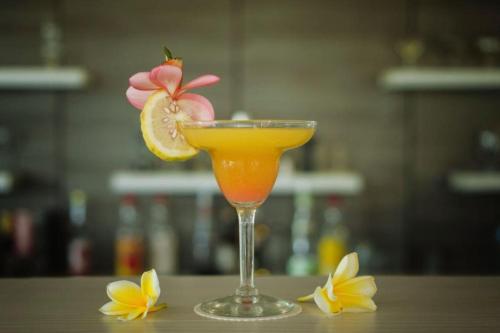 a drink in a glass with a slice of lime and flowers at Celosia 1 BR Superior Room AN23 in Mangsit
