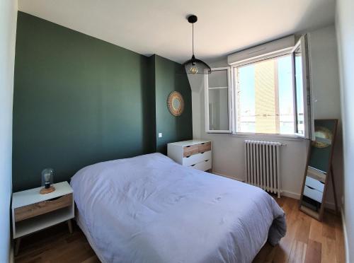 a bedroom with a white bed and a green wall at Au pied des transports Appartement lumineux in Vincennes