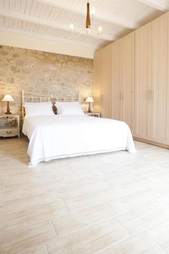 a bedroom with a white bed and a stone wall at Poliana Estate Villas in Riglia