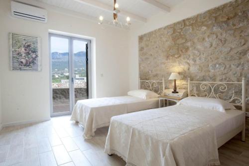 two beds in a white room with a window at Poliana Estate Villas in Riglia