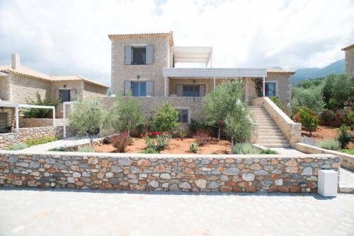 a house with a stone wall in front of it at Poliana Estate Villas in Riglia