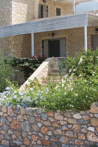 a house with a stone wall and some flowers at Poliana Estate Villas in Riglia