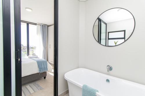 a bathroom with a bath tub and a mirror at 8 at Bella Mare Estate in Gqeberha