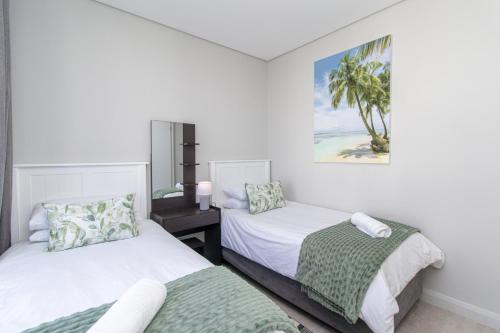 a bedroom with two beds and a picture on the wall at 8 at Bella Mare Estate in Gqeberha