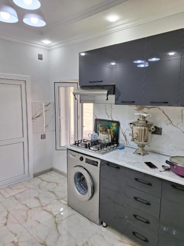 a kitchen with a stove and a washing machine at Rovshan's house in Sheki