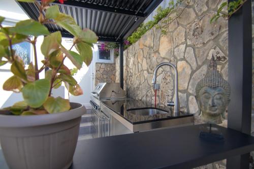 a kitchen with a sink and a stone wall at Apartments Flowers - Heated Pool Near Beach in Krk