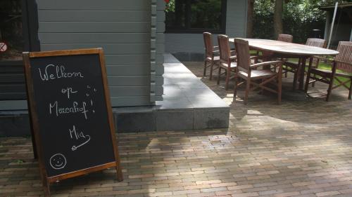 a chalkboard sign in front of a table and chairs at Mezenhof in Brasschaat