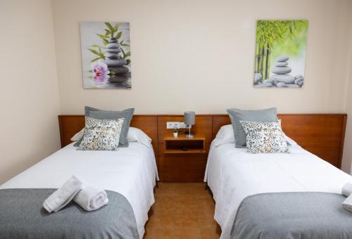 two beds in a room with white and gray at Pensión A Codeseira Melide in Melide