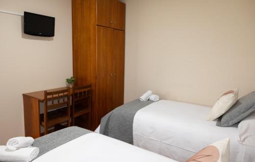 a hotel room with two beds and a tv at Pensión A Codeseira Melide in Melide