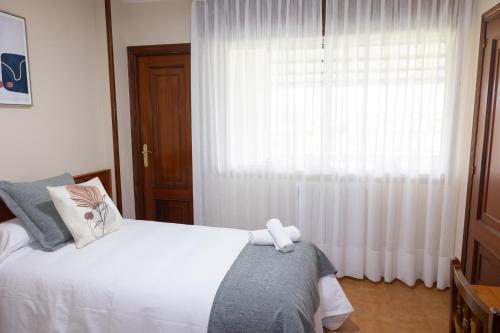 a bedroom with a white bed and a window at Pensión A Codeseira Melide in Melide