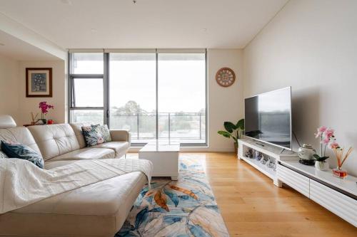 a living room with a couch and a flat screen tv at Macquarie Park Paradise-City View in Sydney