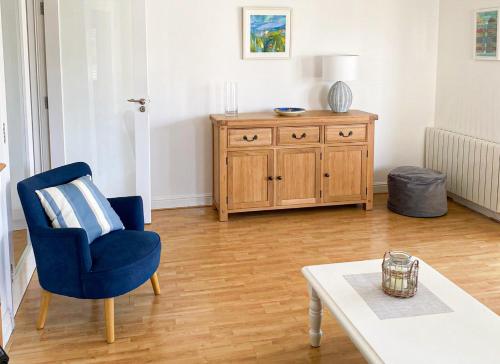 a living room with a blue chair and a table at Moore Bay Holiday Homes No 18A by Trident Holiday Homes in Kilkee