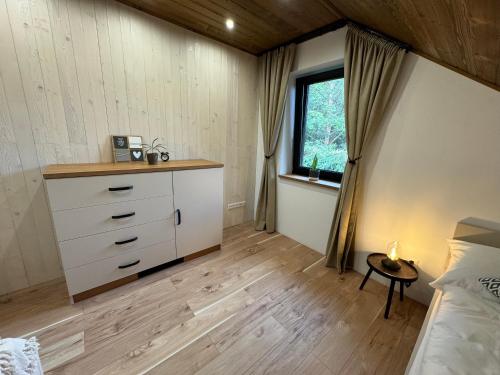 a bedroom with a bed and a dresser and a window at Chata pod Cigerníkom in Matiašovce