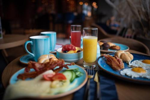 a table topped with plates of breakfast food and orange juice at Mercure Debrecen in Debrecen