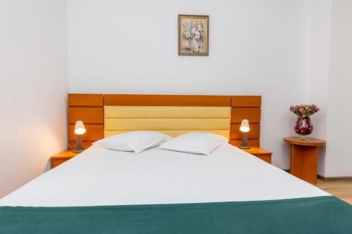 a bedroom with a large white bed with two lamps at Hotel Sir Colentina in Bucharest