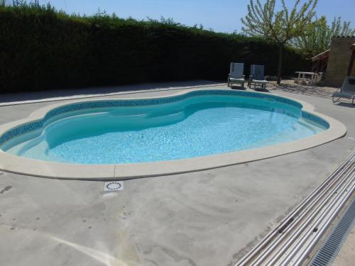 a large swimming pool with two chairs around it at Gite aux Lauriers d'Adhémar in La Garde-Adhémar