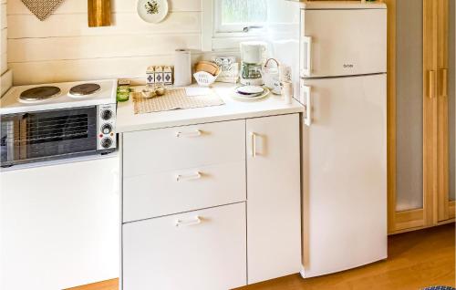 a kitchen with white cabinets and a refrigerator at 1 Bedroom Awesome Home In Frillesås in Frillesås