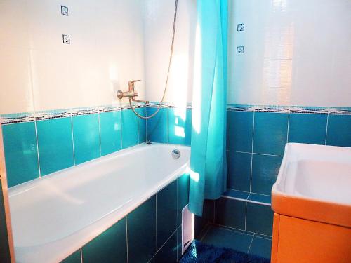 a blue tiled bathroom with a tub and a sink at Apartment Kievskaya 114/2 in Bishkek