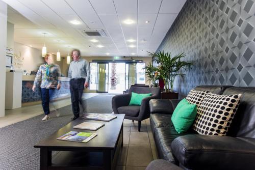 a man and woman walking through a living room at Emerald Hotel in Gisborne