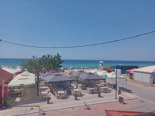 a group of tables and chairs with umbrellas on the beach at Katerina apartment in Nea Plagia