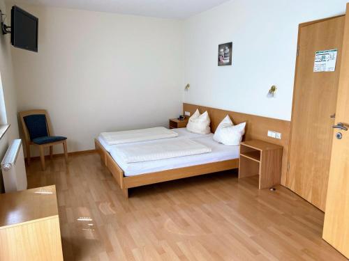 a bedroom with a bed and a chair in it at Pension Zum Bahnhof in Mörlheim