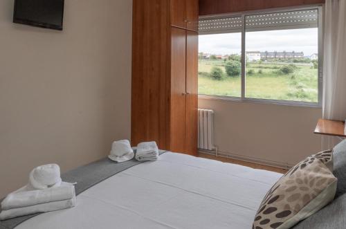 a bedroom with a bed with towels and a window at Pensión A Codeseira Melide in Melide