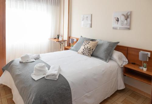 a bedroom with a large white bed with towels on it at Pensión A Codeseira Melide in Melide