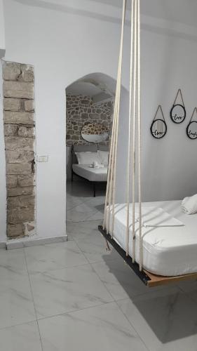 a bedroom with a hanging bed and a stone wall at Polyxeni Apartments & Rooms in Qeparo