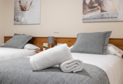 two beds with towels on top of them at Pensión A Codeseira Melide in Melide