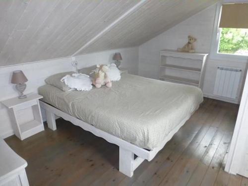 - un ours en peluche assis sur un lit dans une chambre dans l'établissement La voile blanche, à Berneval-le-Grand