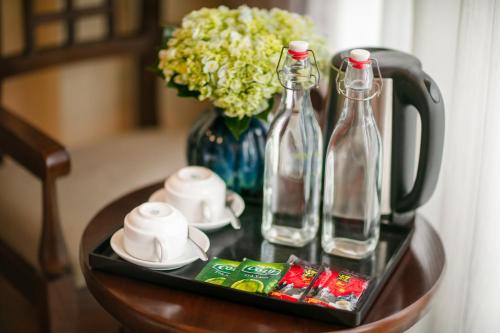 a table with two bottles and a vase with flowers at The West Hotel & Spa in Hanoi