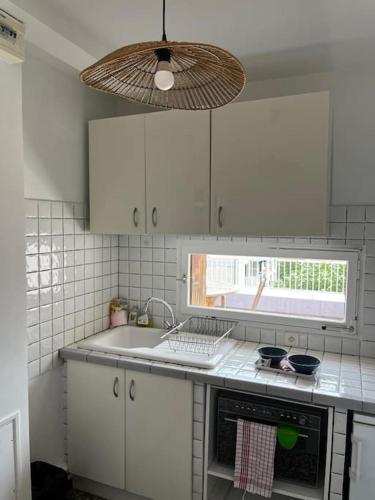 une cuisine avec des armoires blanches, un évier et une fenêtre dans l'établissement Apt proche des Calanques, à Marseille