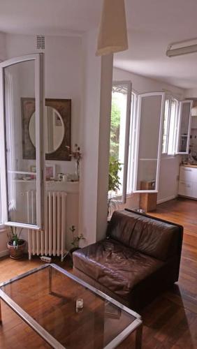 un salon avec un canapé en cuir et une table en verre dans l'établissement Charmant Appartement avec cour privée, à Aubervilliers
