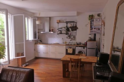 une cuisine avec une table et une cuisine avec une cuisinière dans l'établissement Charmant Appartement avec cour privée, à Aubervilliers