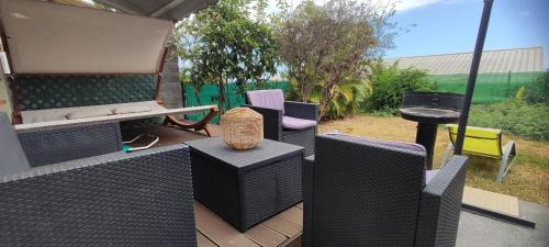 eine Terrasse mit Stühlen, Grill und Tisch in der Unterkunft Chez NOUS in Saint-Paul