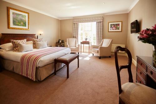 a bedroom with a bed and a table and chairs at Tylney Hall Hotel in Hook