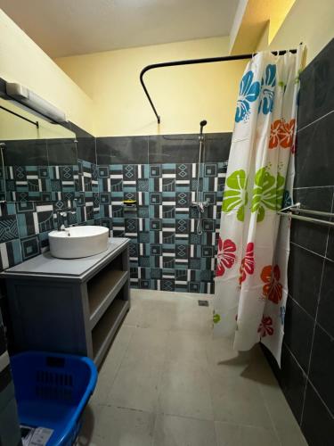 a bathroom with a sink and a shower curtain at Hôtel - Appartement meublé " LES FLOTS BLEU " in Antananarivo