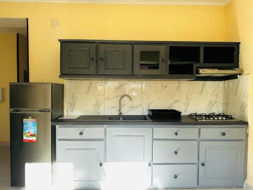 a kitchen with white cabinets and a stainless steel refrigerator at Hôtel - Appartement meublé " LES FLOTS BLEU " in Antananarivo