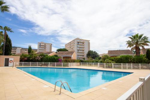 une grande piscine avec des bâtiments en arrière-plan dans l'établissement Lou Estrella - Appt 4p avec piscine proche plage, au Lavandou