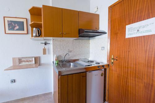 a small kitchen with wooden cabinets and a sink at Dionisos Roses in Paralia Dionysiou