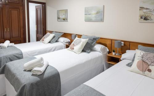 a group of three beds in a room at Pensión A Codeseira Melide in Melide