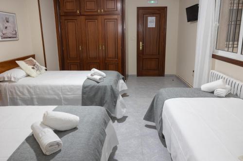 a room with three beds with towels on them at Pensión A Codeseira Melide in Melide