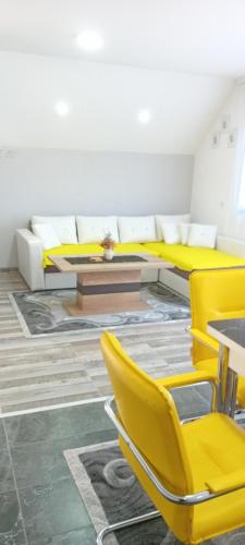 a room with yellow chairs and a table at Apartmani Romansa Perucac in Perućac